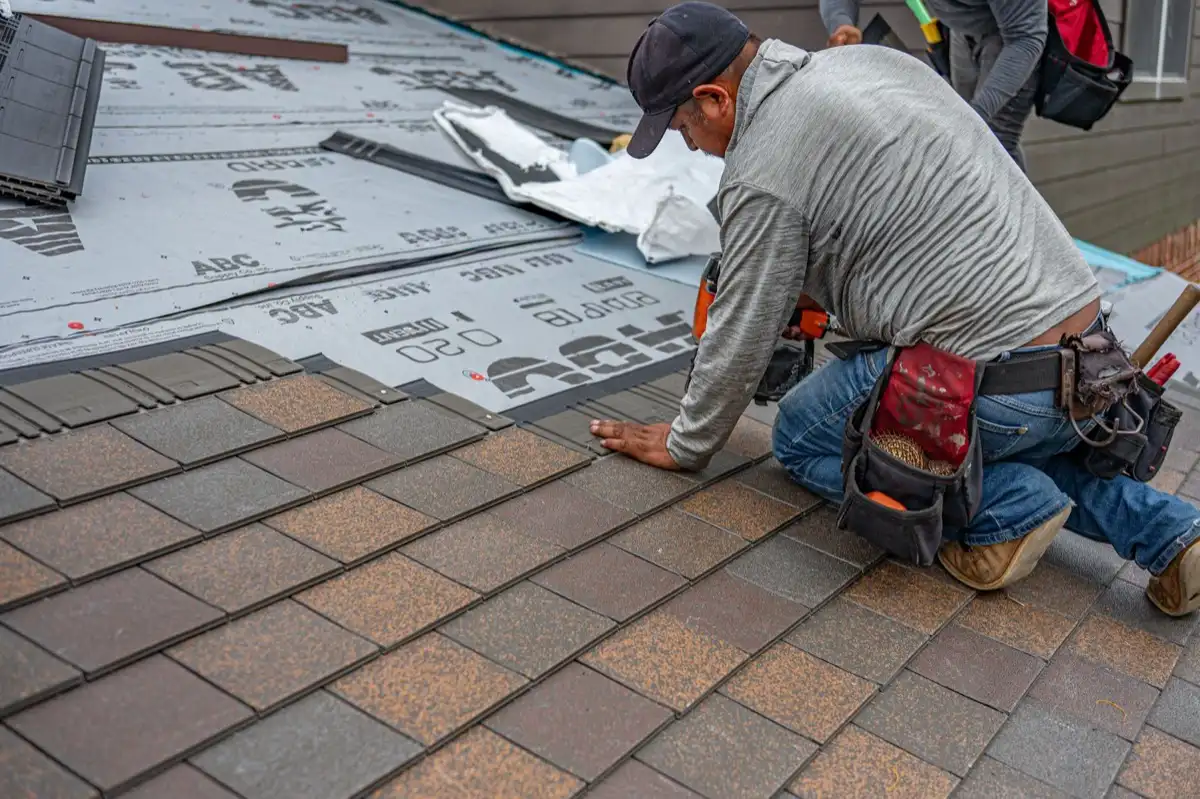 Roofing installer fastening shingles over new underlayment in Boulder, CO